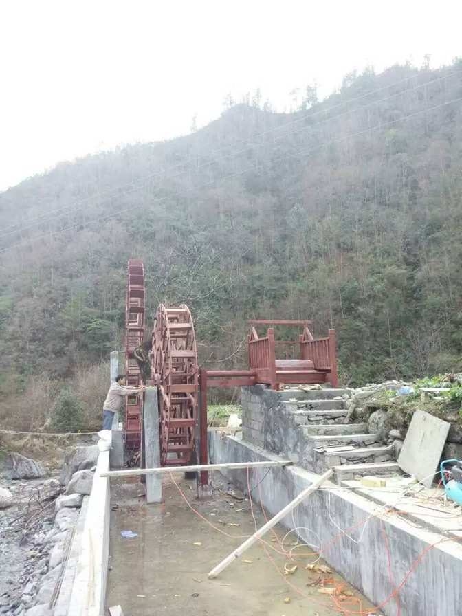 四川资中大型仿古水车红色施工中河边石墙_大型仿古水车定制厂家_大型仿古水车红色施工中河边石墙传统木作工人脚手架水流树木山脉房屋