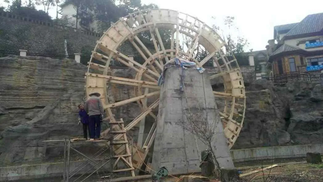 河北保定大型仿古水车原木色单轮施工中传统木作_大型仿古水车定制厂家_大型仿古水车原木色单轮施工中传统木作水流护栏古建背景树木道路房屋工人脚手架